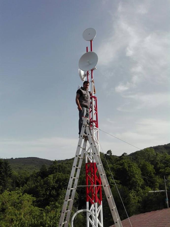 Franco Cerminara in cima a un traliccio mentre installa un’antenna